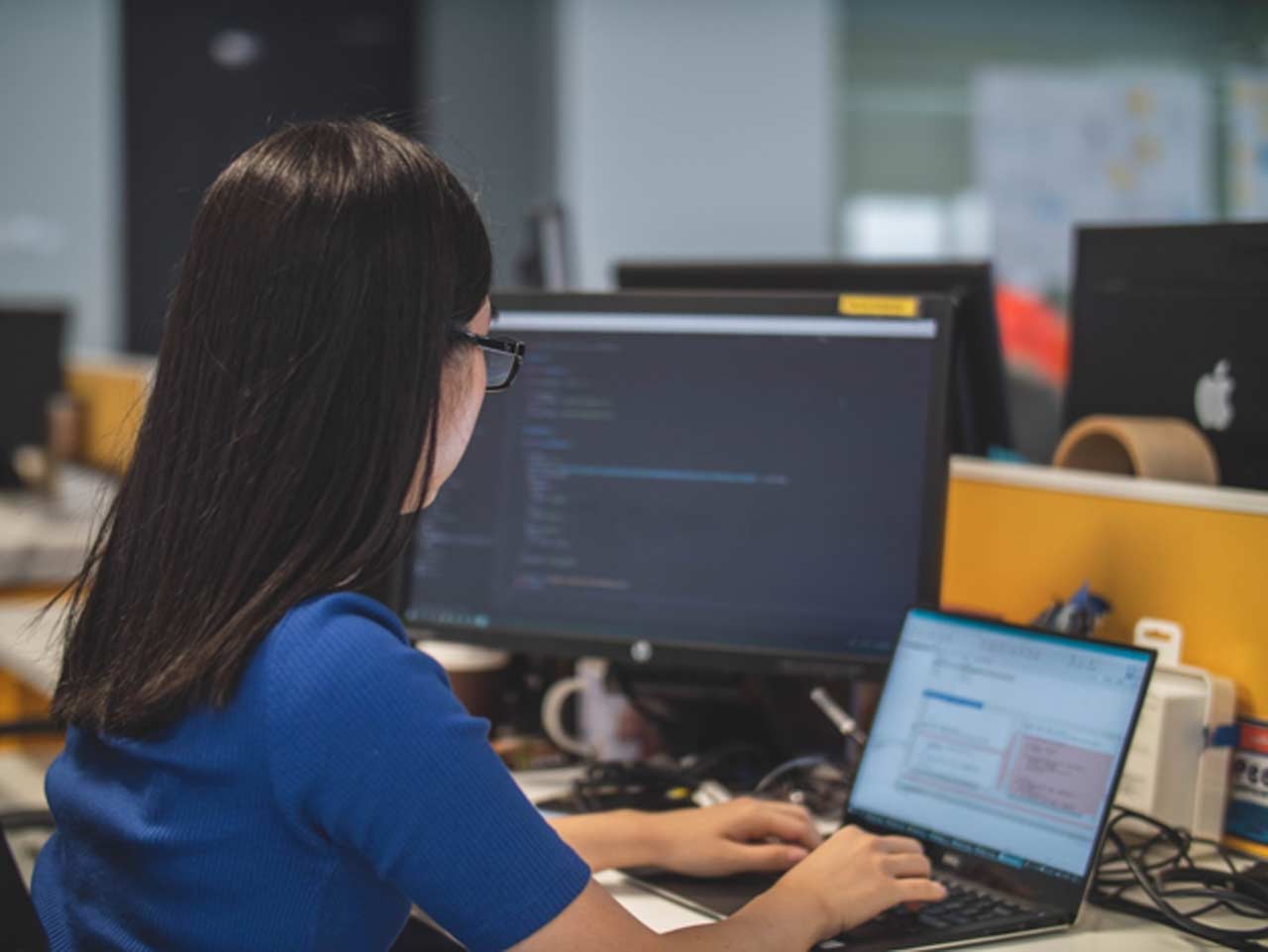 A woman in an office researching proposal management on her computer
